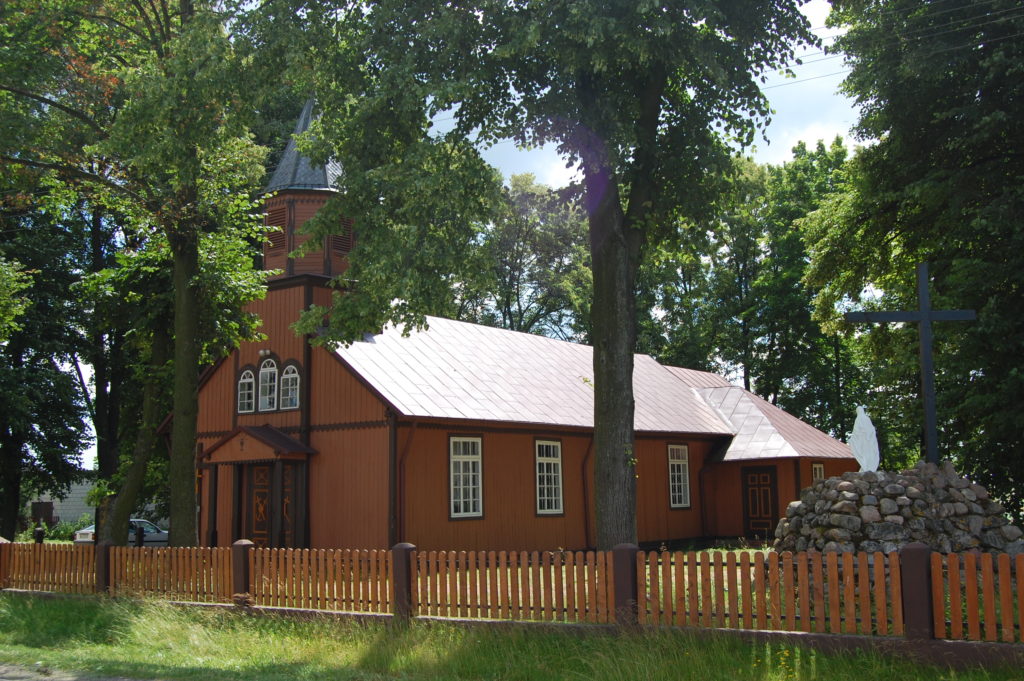 Église de village polonais typique entourée d'arbres.